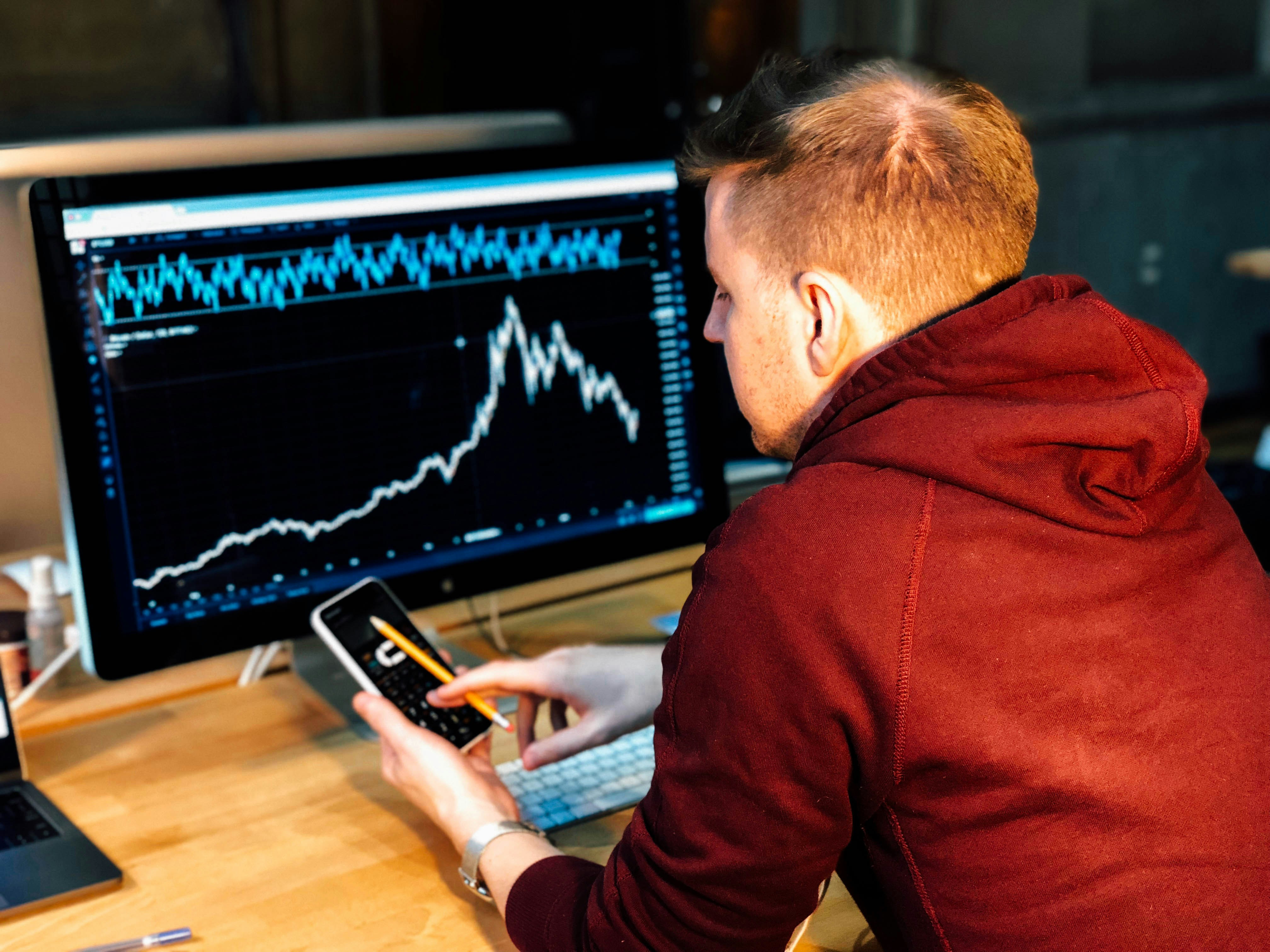 inversionista analizando gráfica de bolsa con calma, decisión entre retener o vender posiciones en mercado volátil