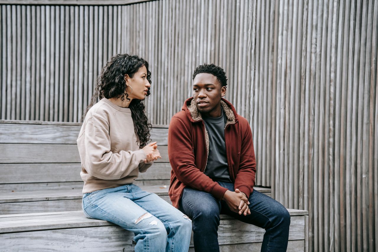 Pareja en conversación seria trabajando para reconstruir la confianza tras una infidelidad financiera