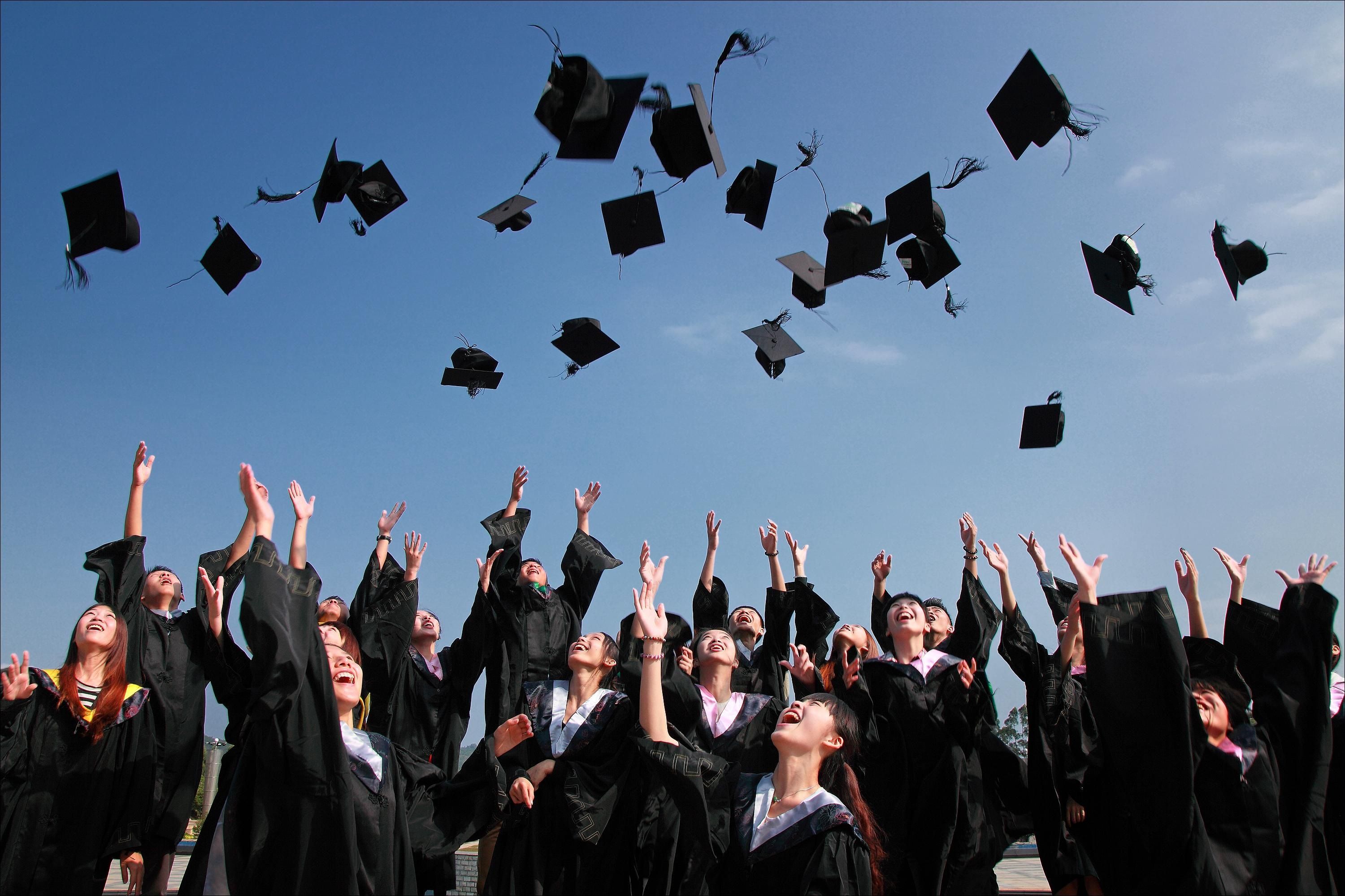 Estudiantes lanzando su birrete al aire tras su graduación, representando el objetivo del fondo de educación universitaria de Dave Ramsey