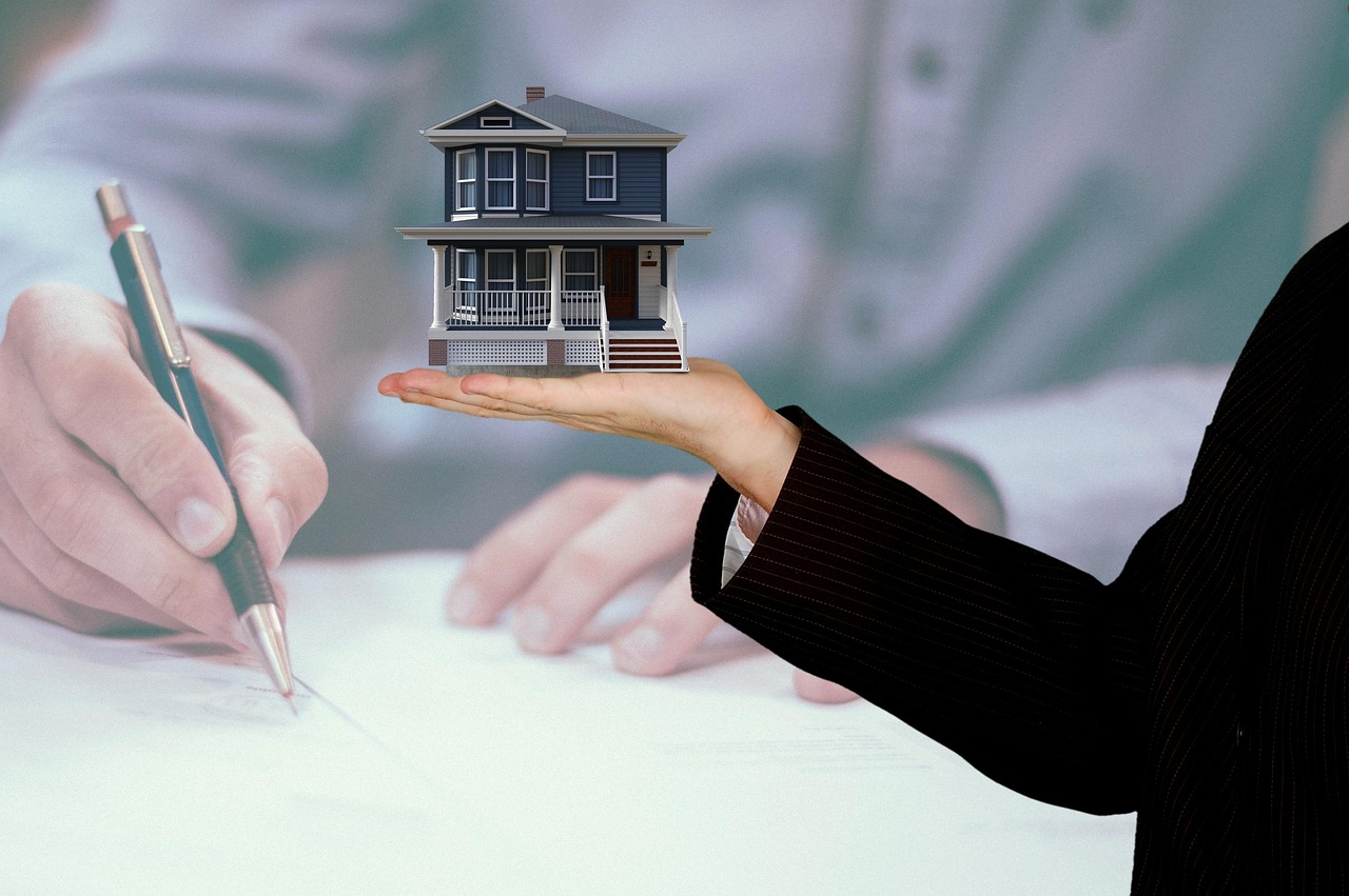 Persona firmando documento mientras otra sostiene una casa como metáfora de prejuicios de comprar o rentar casa