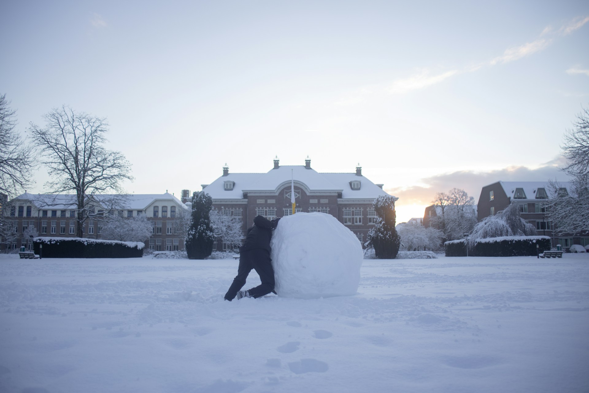 Persona empujando una gran bola de nieve en un paisaje nevado, metáfora del método bola de nieve de Dave Ramsey para pagar deudasDijiste: Siguiente post: Completa tu fondo de emergencias (Dave Ramsey – Paso de Bebé 3)