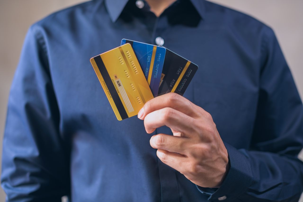 Persona examinando tarjetas de crédito, decidiendo cuál elegir