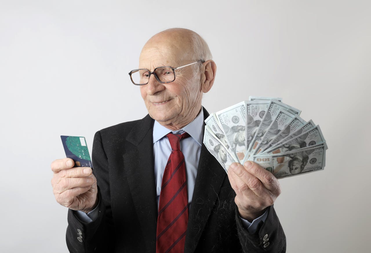 Persona con una tarjeta de crédito en una mano y billetes en el otro en señal de que está reparando su crédito