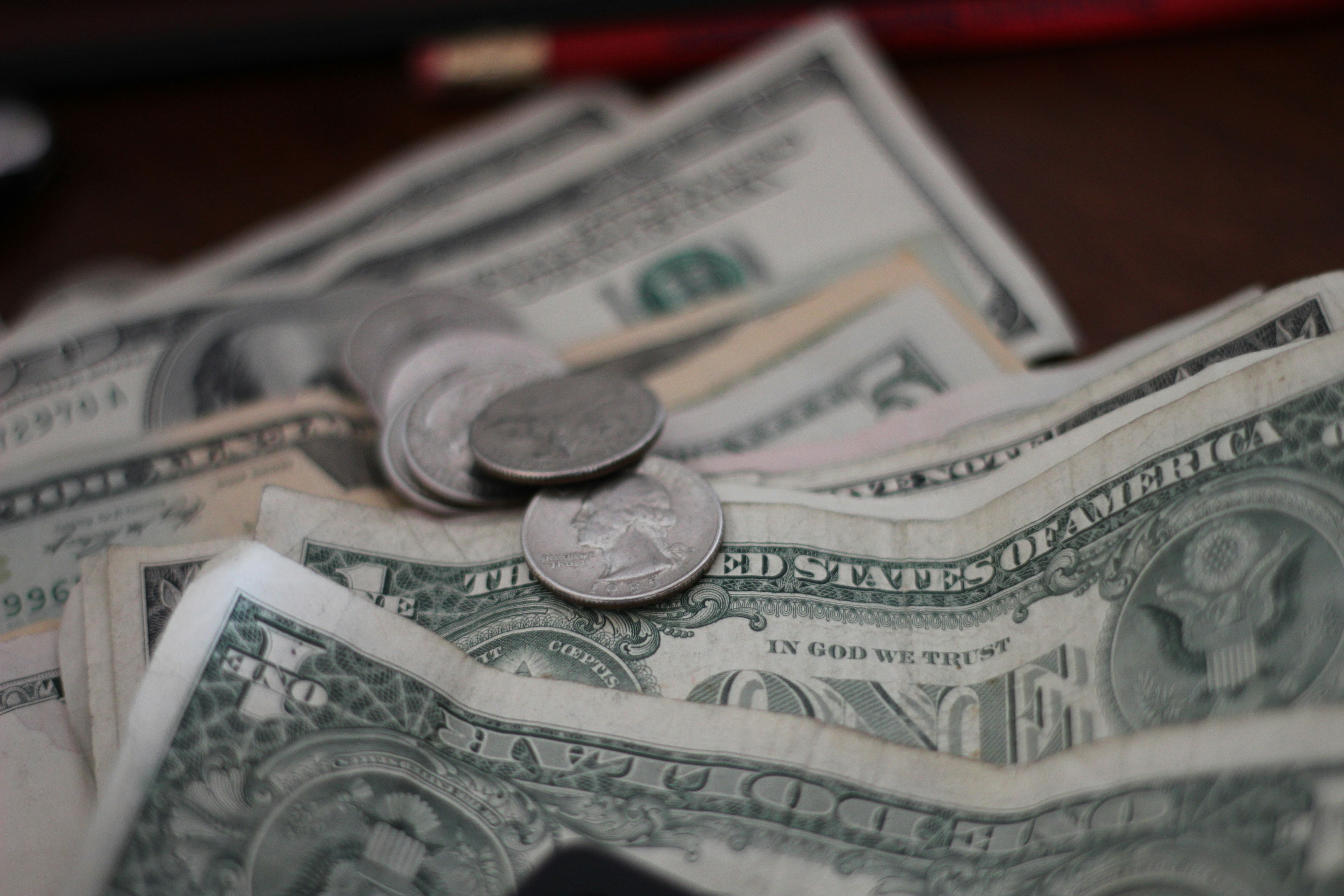 Monedas y billetes sobre escritorio como estrategias para tener más dinero a fin de mes