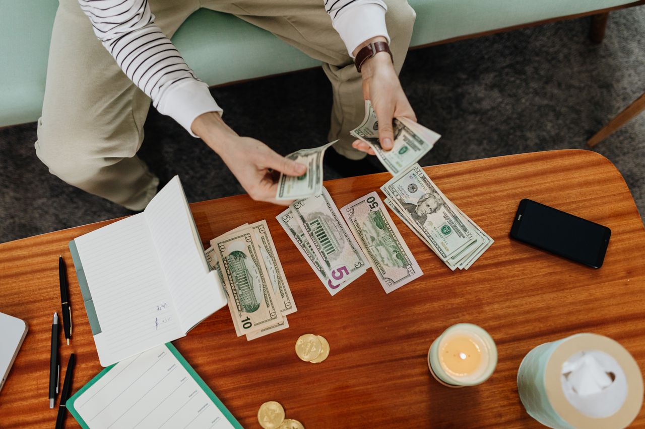 Persona separando billetes en su escritorio, representando el primer paso de bebé de Dave Ramsey para construir un fondo de emergencias