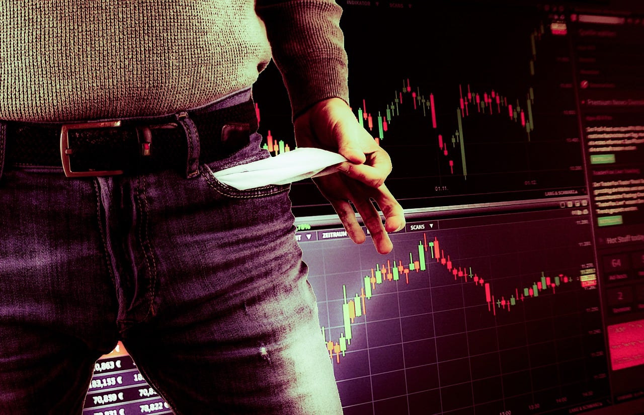 Persona con bolsillos vacíos enfrente de una terminal Forex porque perdió todo su dinero en el mercado de divisas