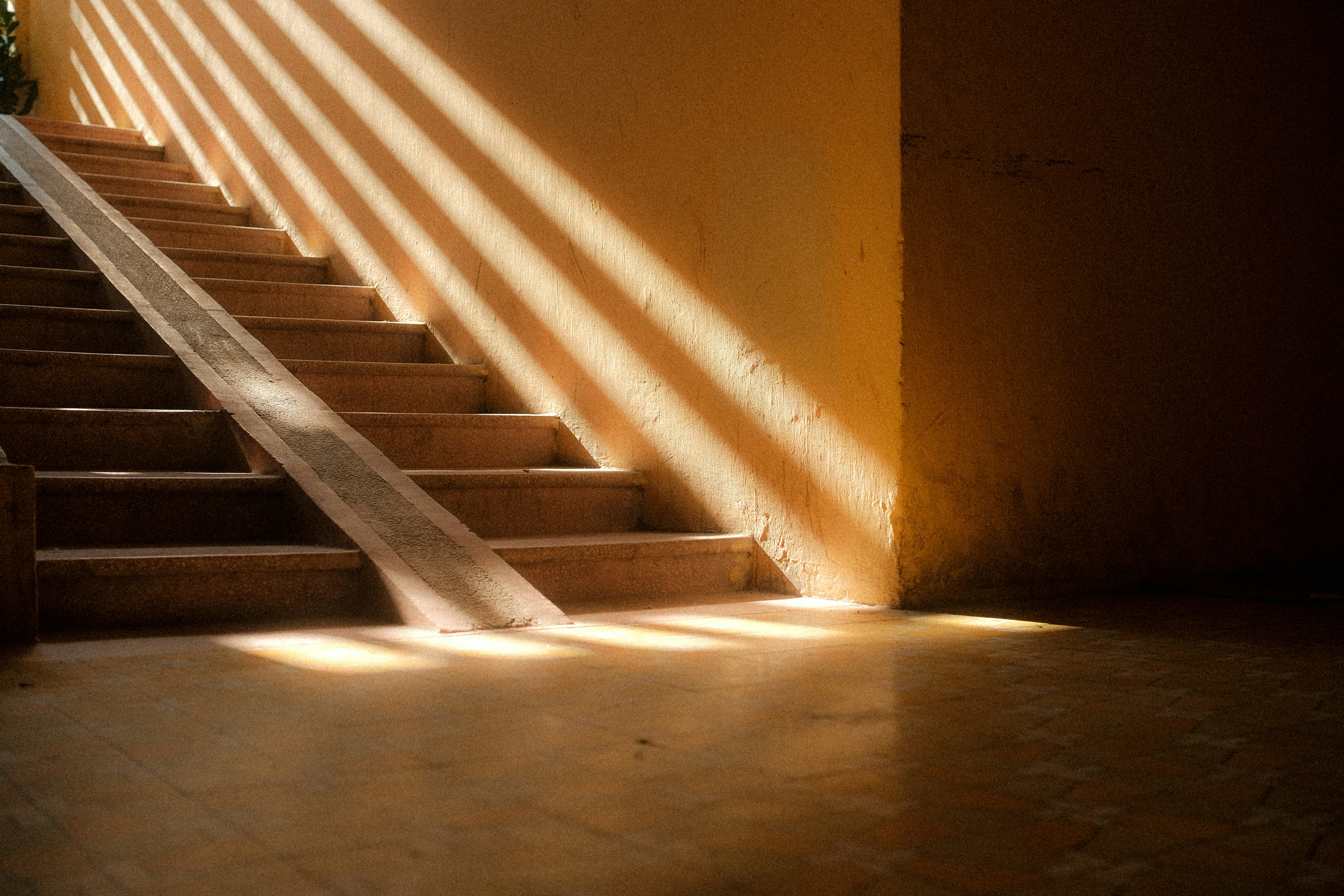 escalera de piedra que asciende hacia la luz, metáfora del crecimiento del patrimonio a largo plazo con interés compuesto