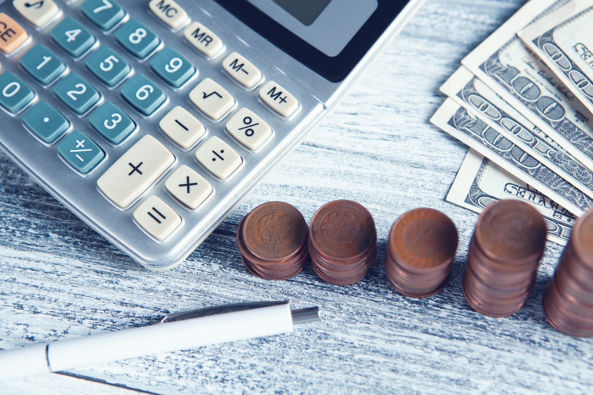 calculadora, pluma, pila de monedas creciente y billetes representando planeación para el retiro y aprovechamiento de estímulo fiscal al ahorro para el retiro