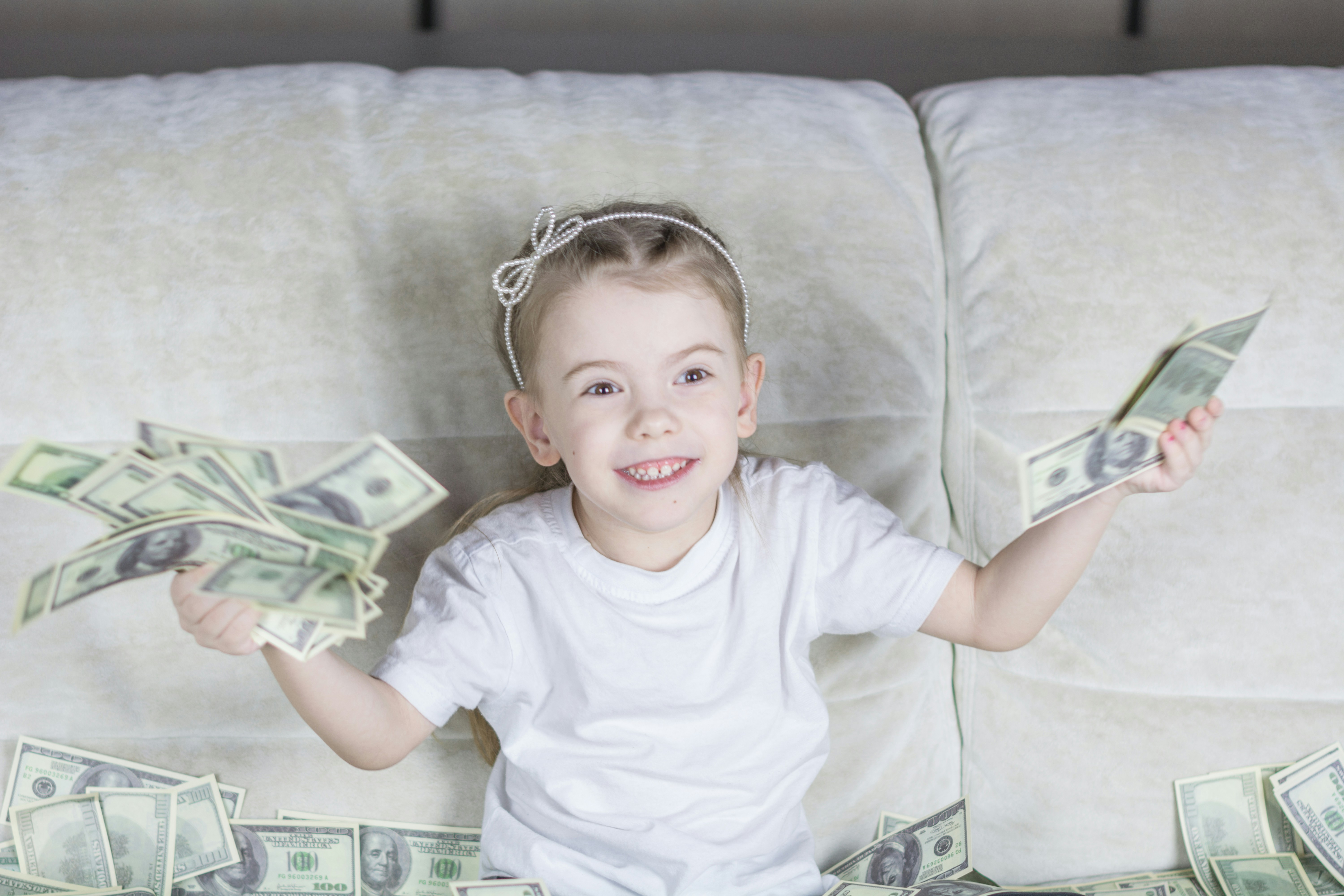 Niña con muchos billetes dada la importancia de empezar a invertir a edad temprana