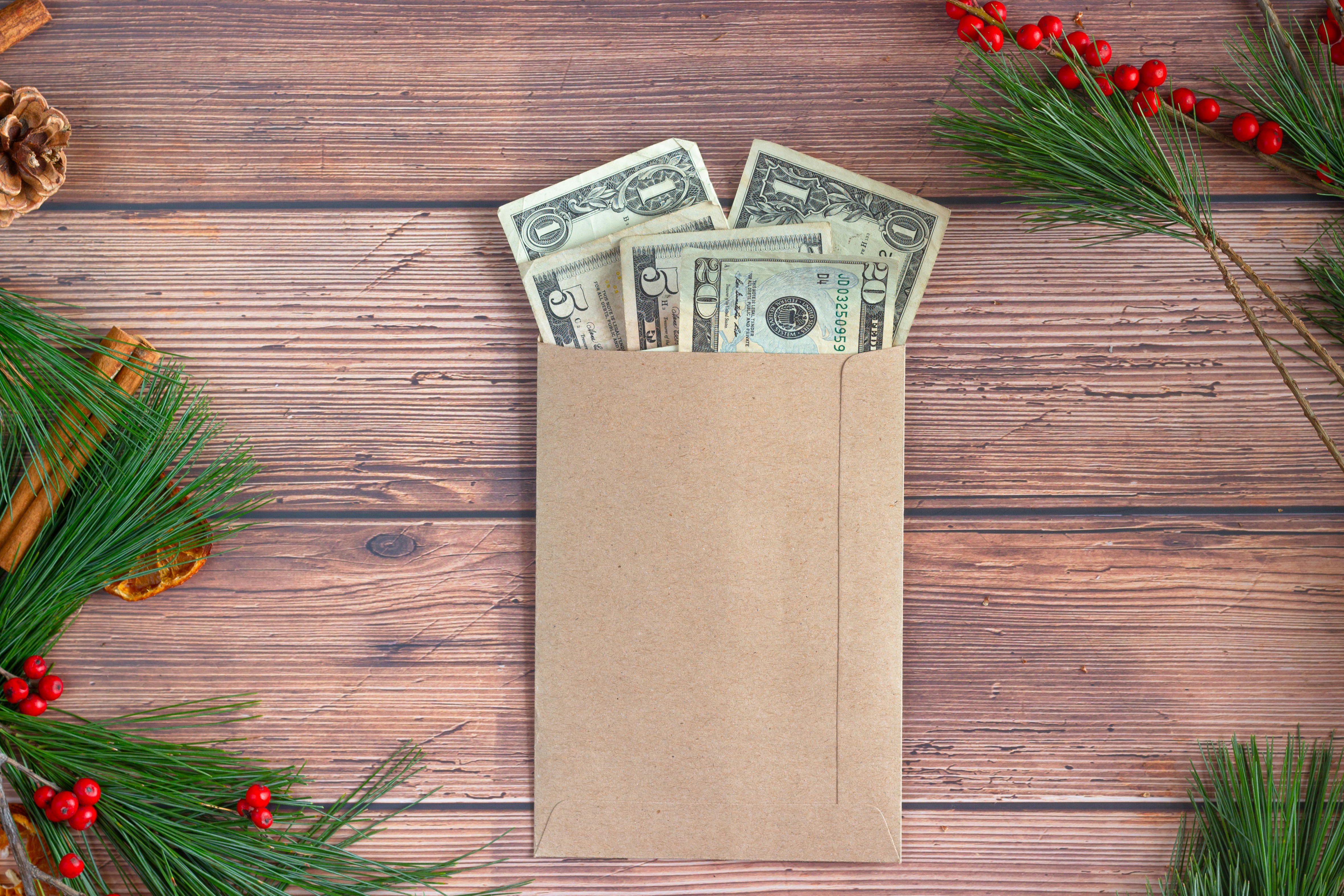 Sobre con dinero junto a decoraciones navideñas representando el aguinaldo y cómo aprovecharlo