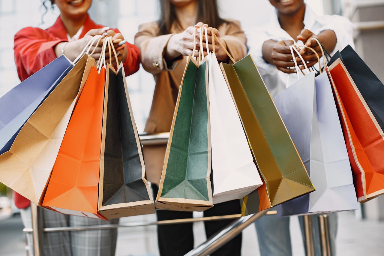 Tres personas con varias bolsas de compras, que ilustra los riesgos de gastar de más durante el Buen Fin.