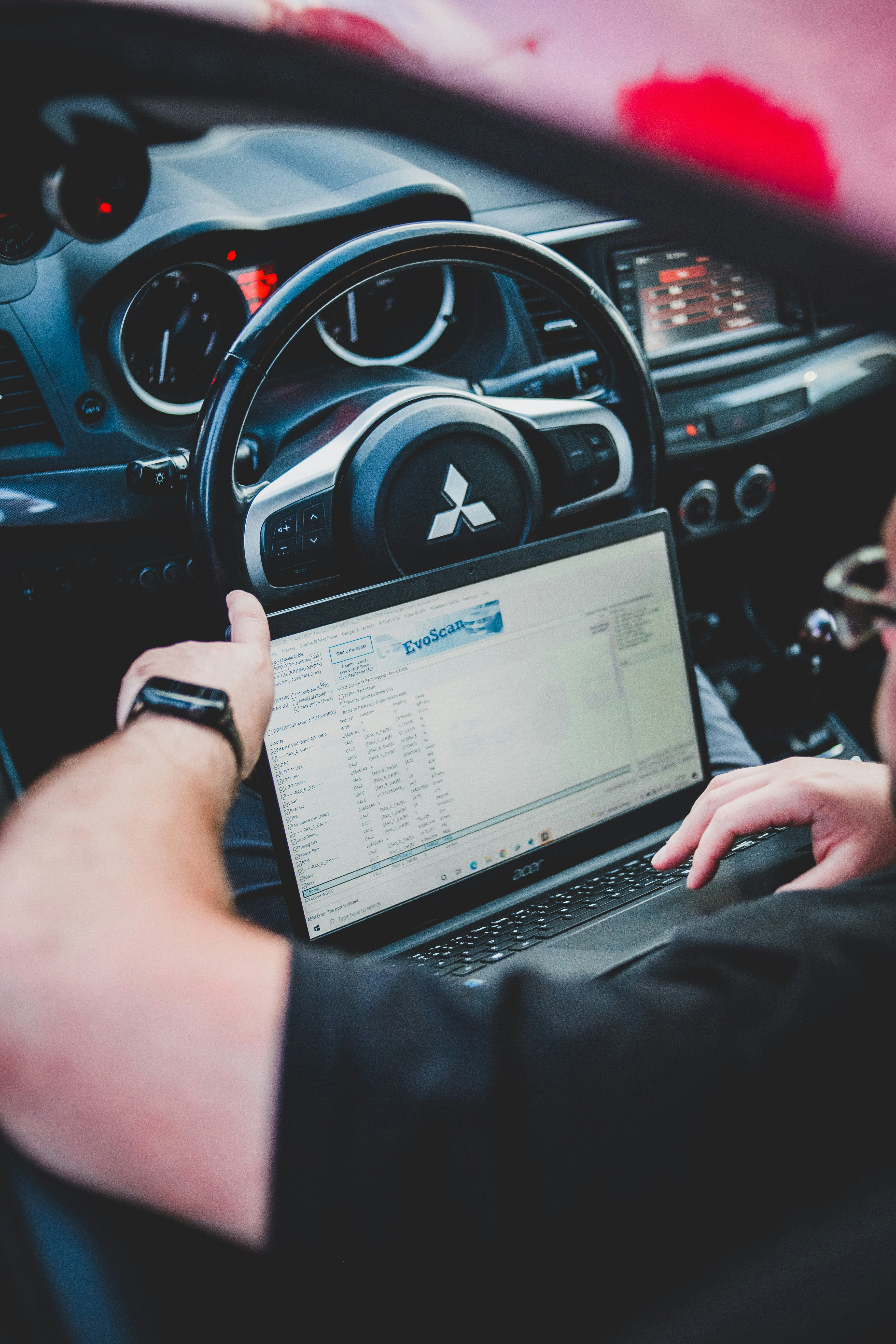 Persona con laptop en su auto cotizando su seguro