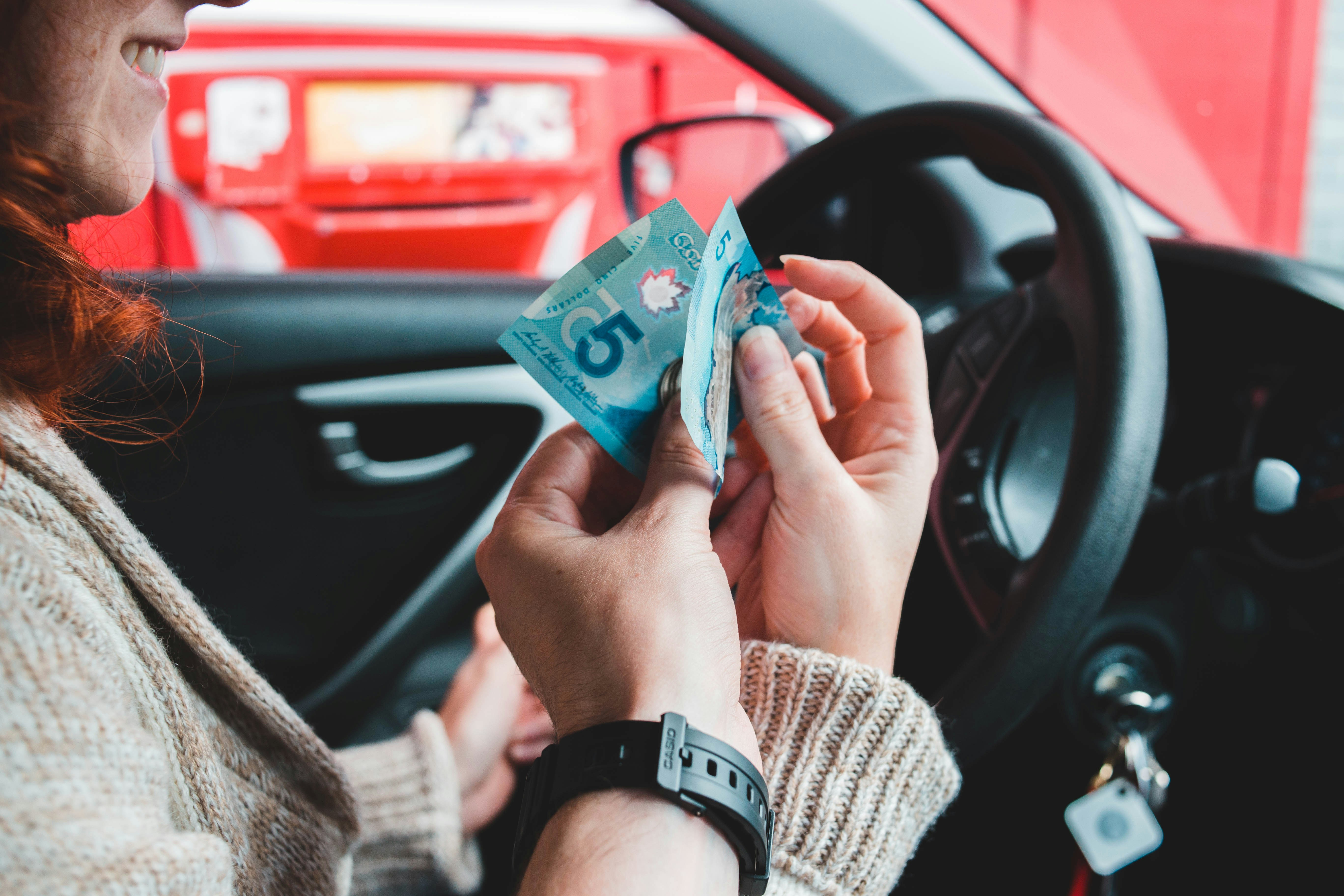 Persona en un coche con efectivo pensando en abonar a capital a su crédito automotriz
