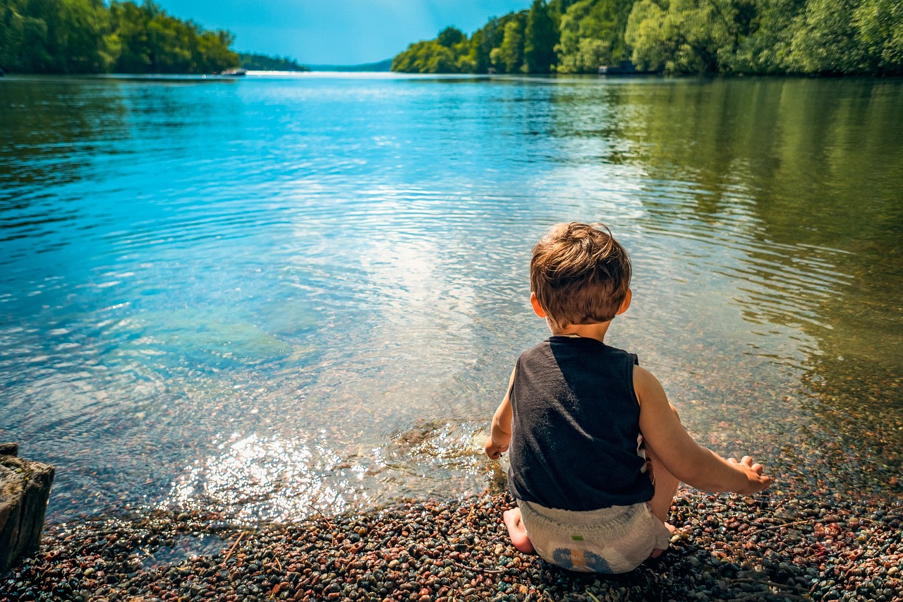 Niño sentado tranquilo mirando al lago y al horizonte, porque nunca eres demasiado joven para planear tu retiro a largo plazo