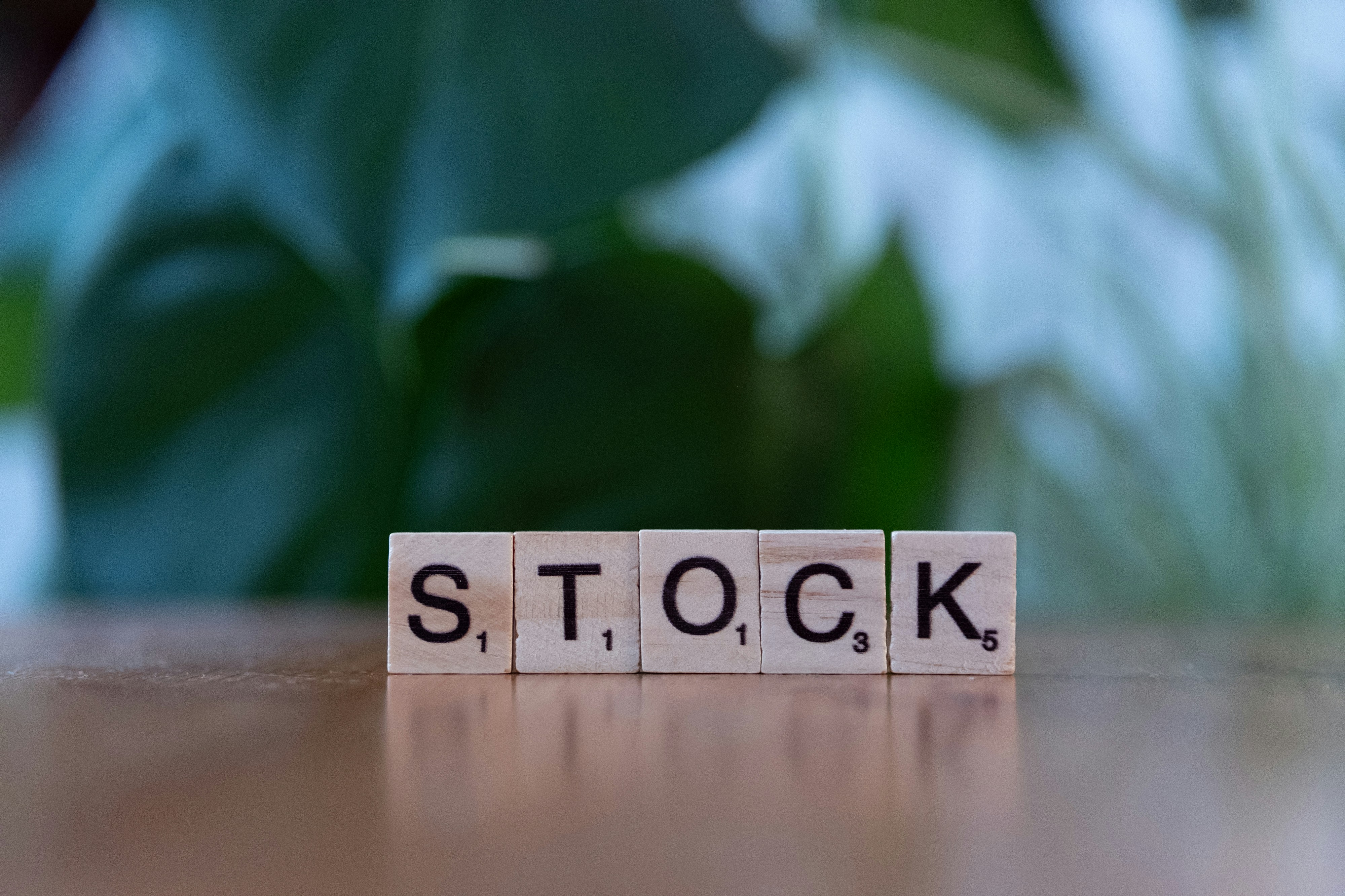 Palabra "stock" (acciones) en fichas de scrabble representando personas que apenas están formando su noción para invertir en acciones a largo plazo