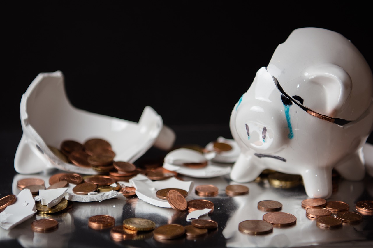 alcancía rota, llorando, con monedas sobre la mesa que ilustra una posible crisis y la preparación que es clave para enfrentarla adecuadamente, con solidez financiera, sin tomar decisiones por miedo