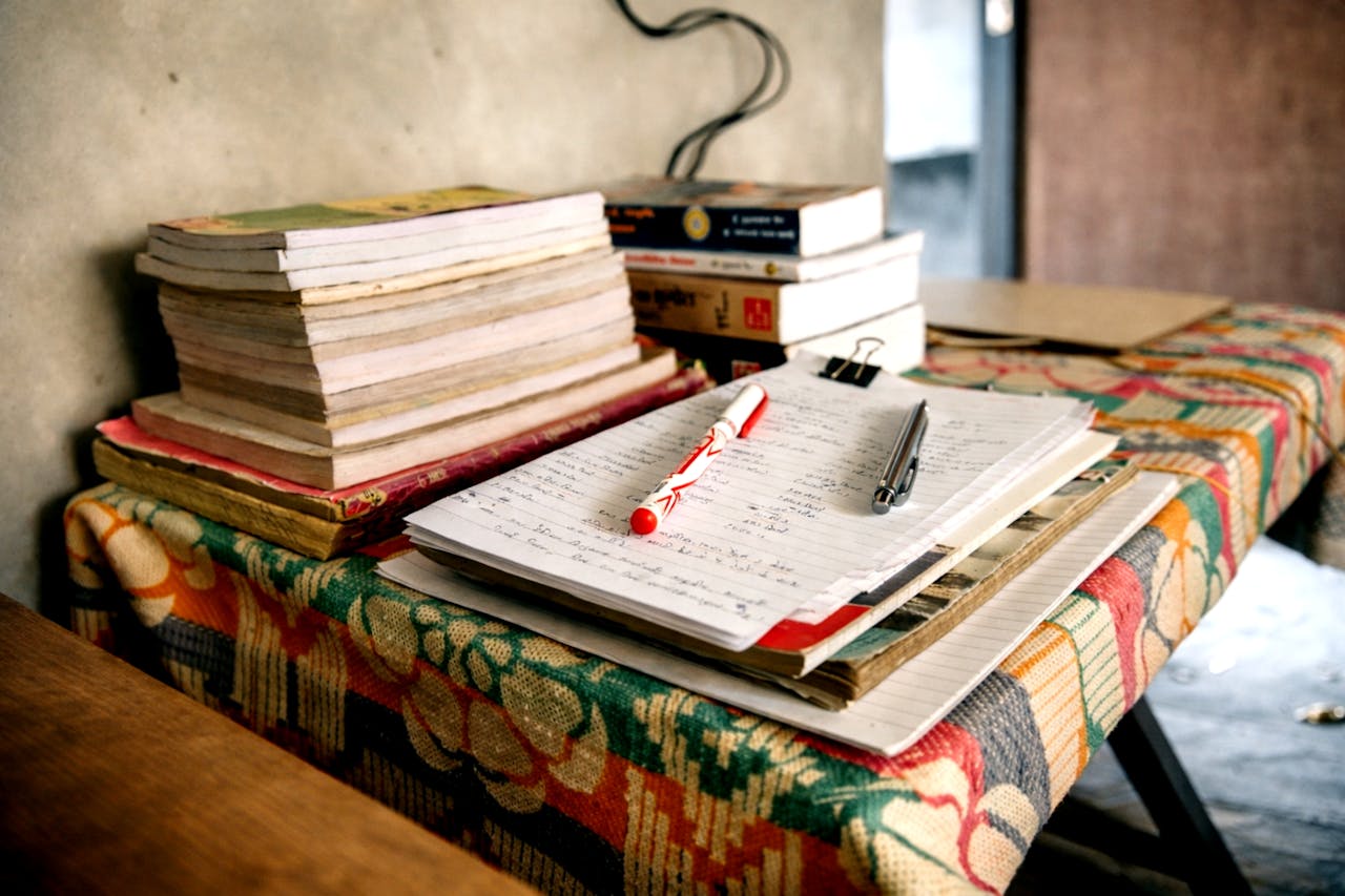 Cuaderno abierto con notas escritas a mano y libros apilados, representando el proceso de autoformación en economía y finanzas personales